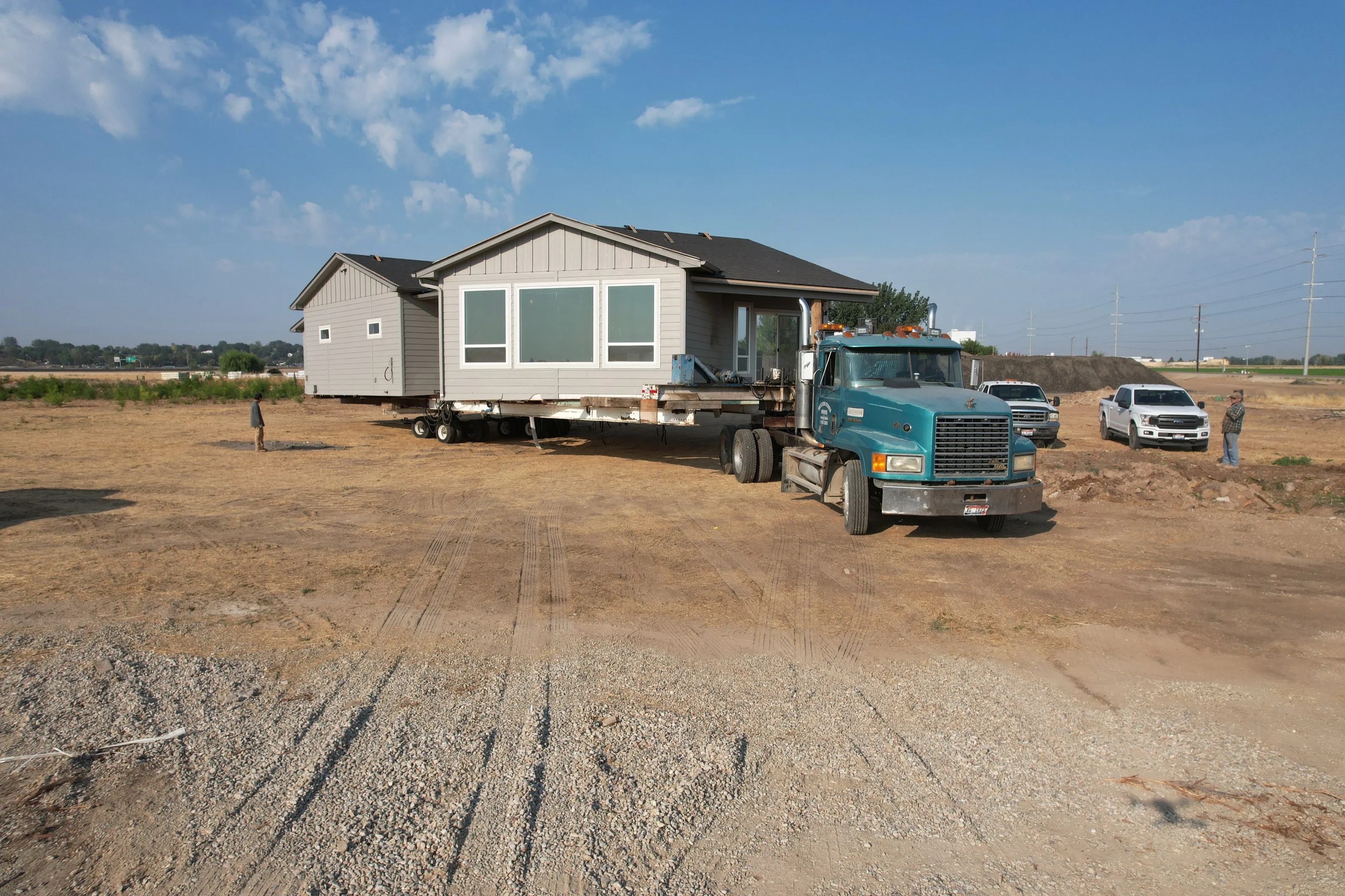 A house on a trailer with an escort truck on a country road