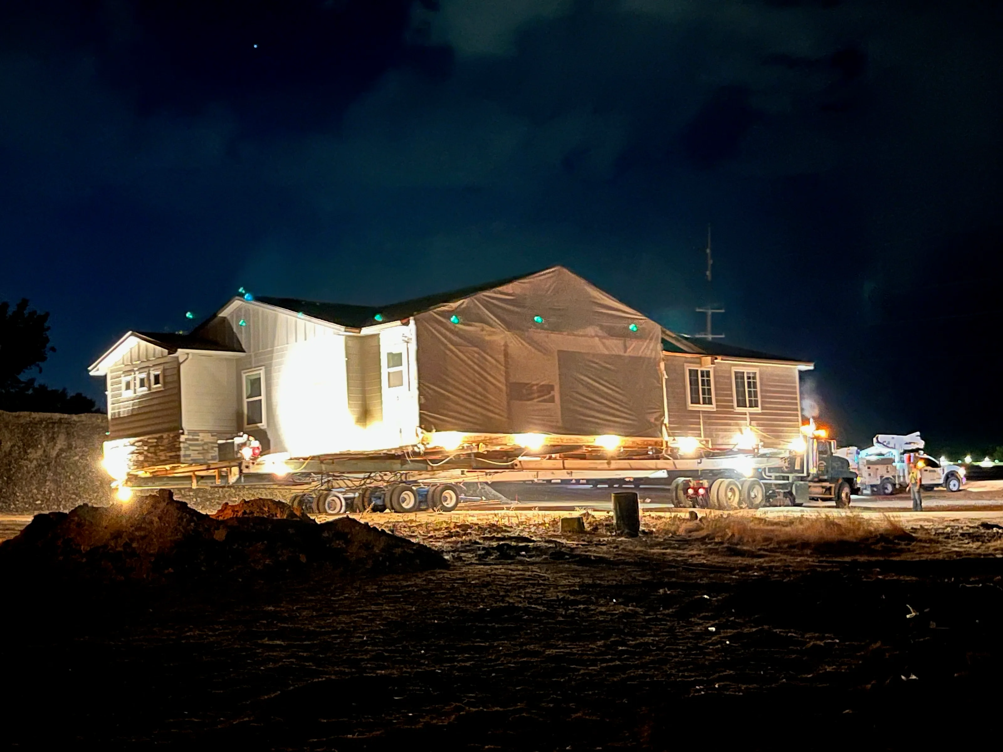 A house lit by work lights, moving through the night