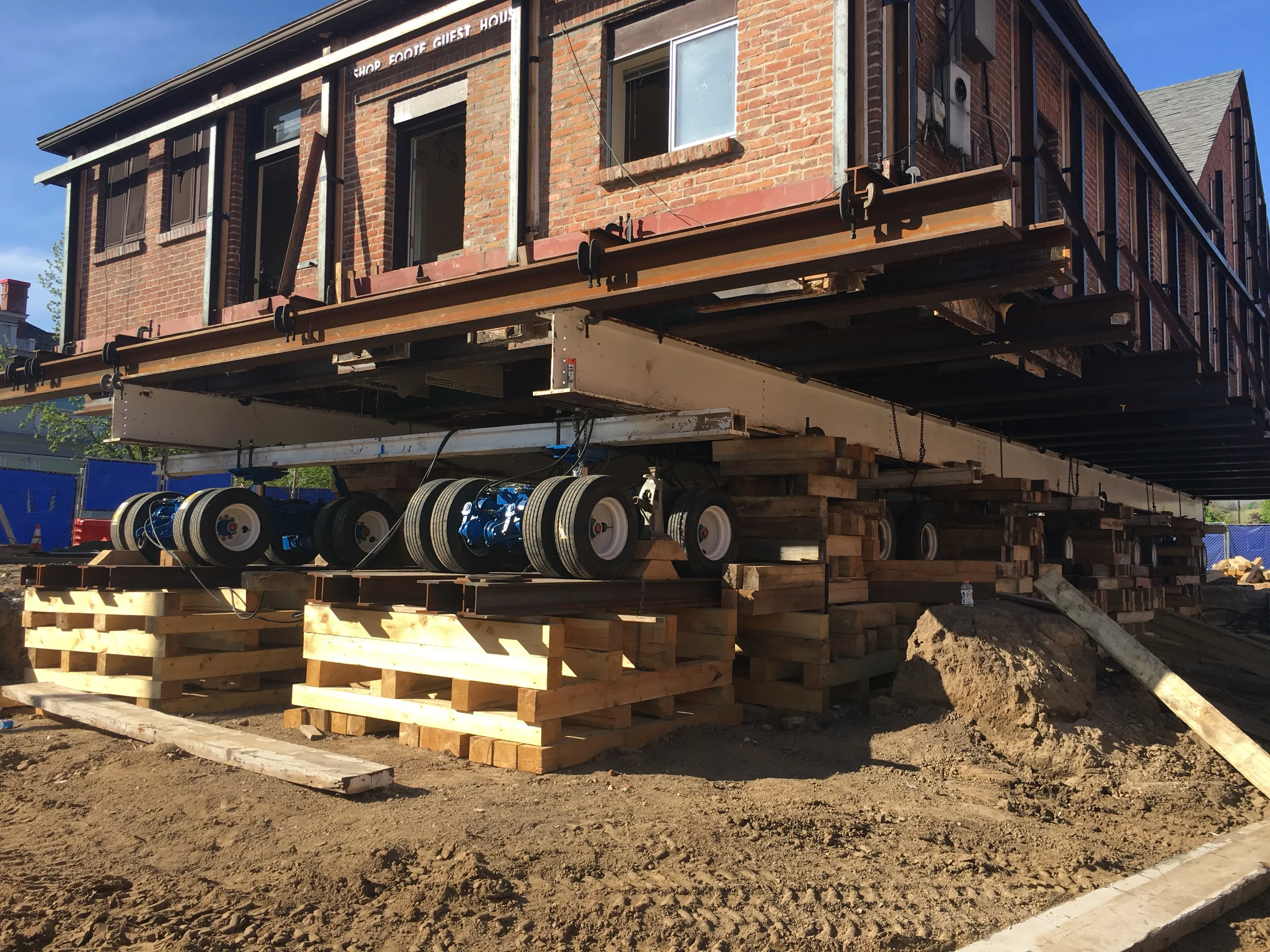 A brick building riding a train of hydraulic dollies, side view