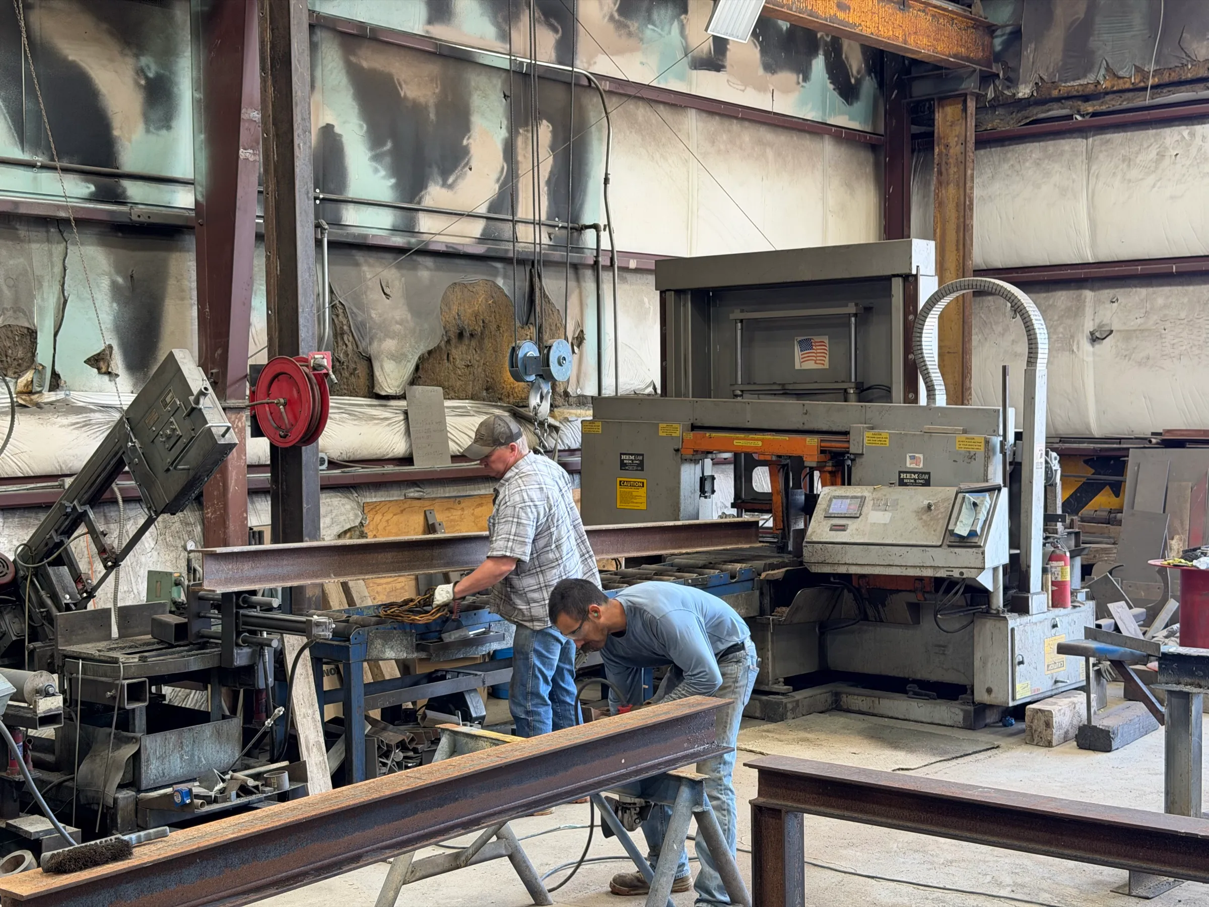 Crew cutting a structural steel I-beam on the horizontal band saw