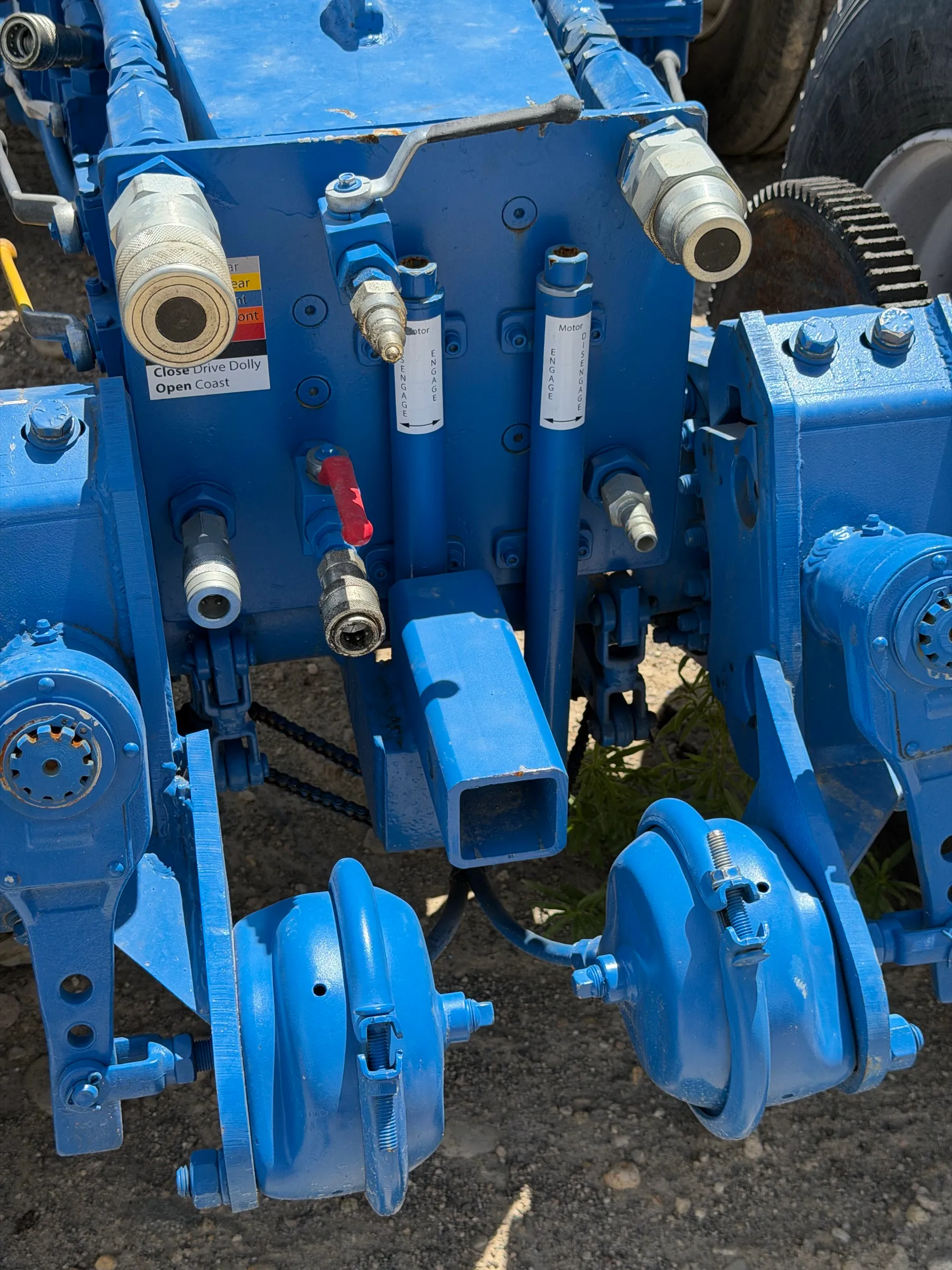 Close-up of hydraulic lines, fittings, and gauges on a moving dolly built in-house