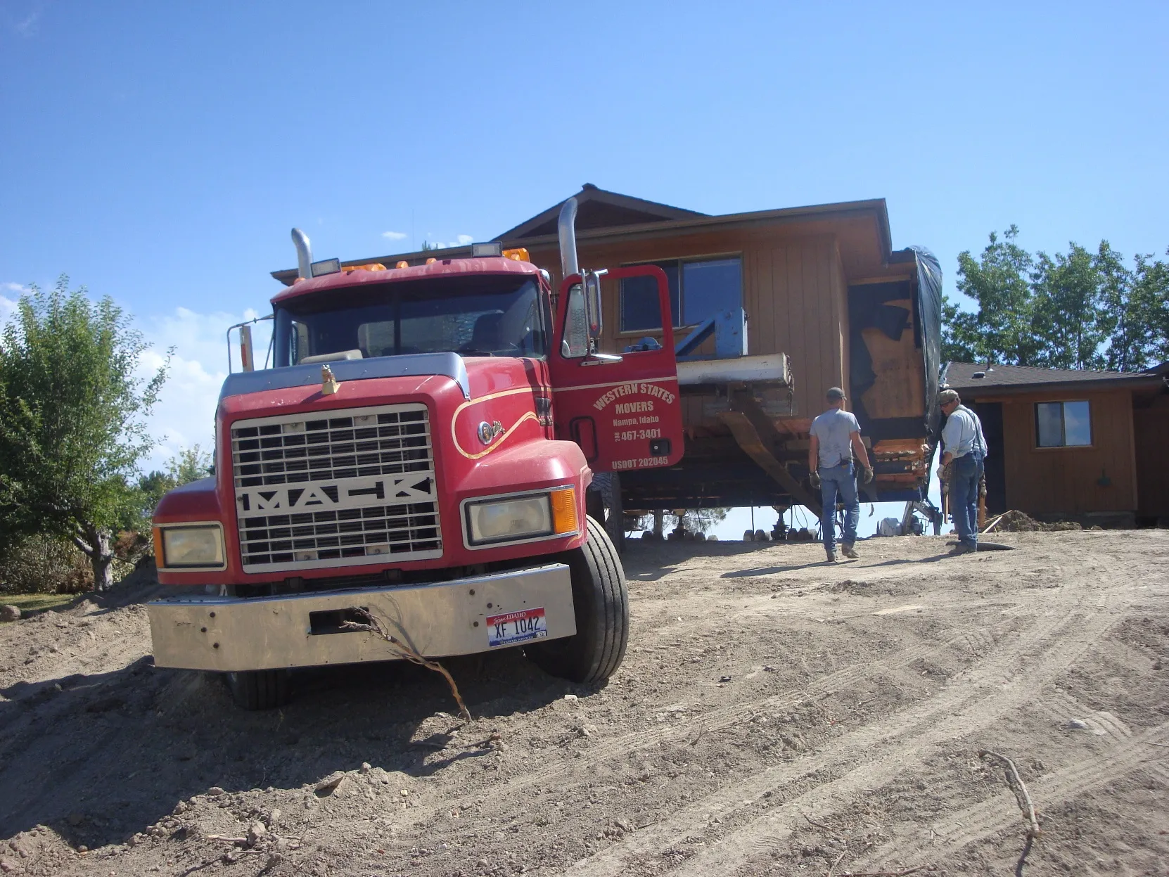 Red Mack truck head-on with the house behind
