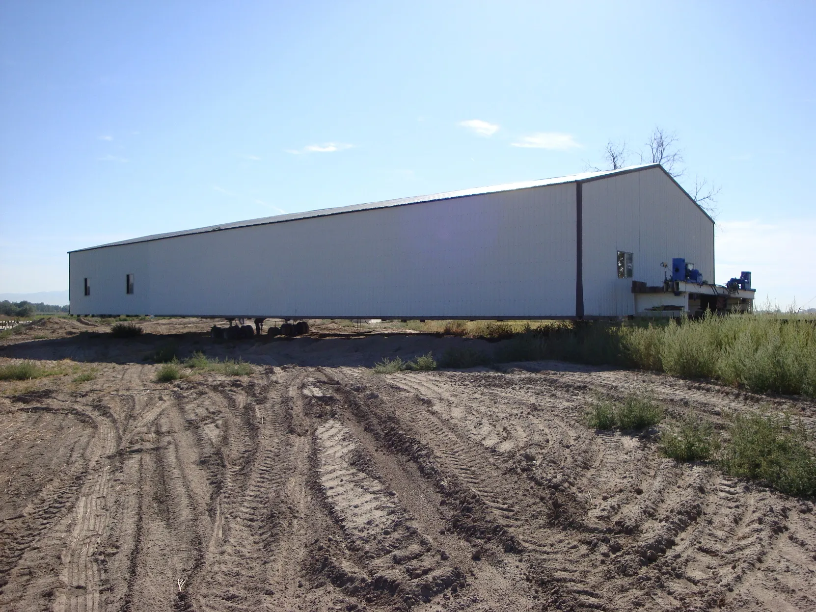 Long white metal shop building under blue sky