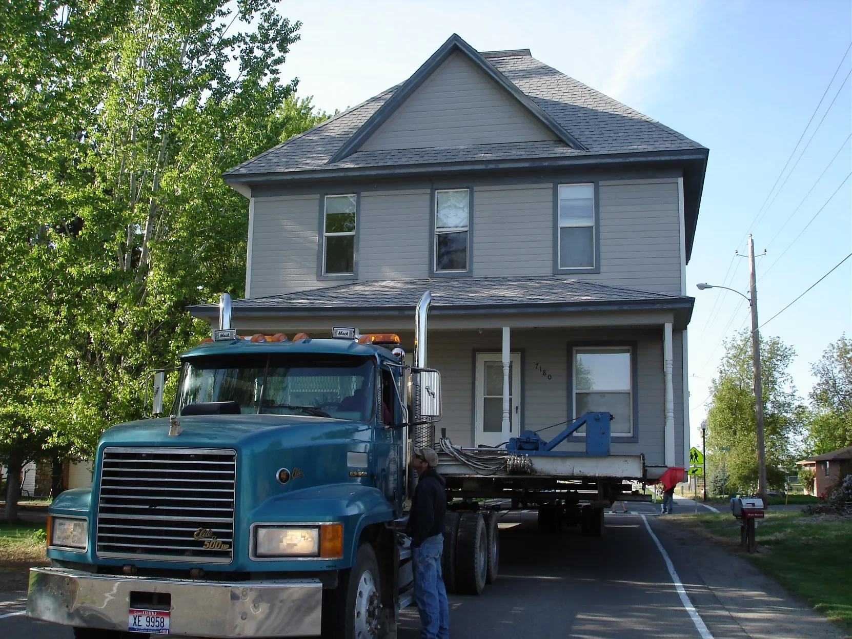 Grey two-story house on the truck among trees